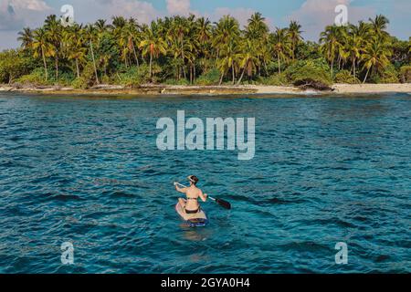 Weibliche SUP-Surferin im Meer in der Nähe des Wüstenstrandes auf den Malediven Stockfoto