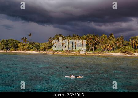 Männlicher Surfer im Ozean in der Nähe des Wüstenstrandes auf den Malediven Stockfoto