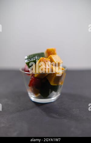 Glas mit farbenfroher mexikanischer Fruchtpaste auf schwarzer Oberfläche Stockfoto