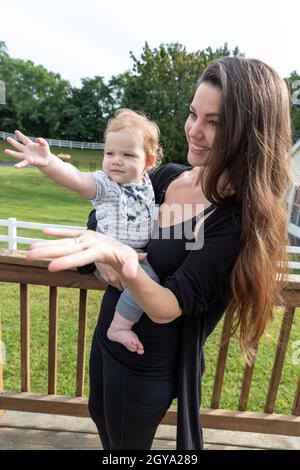 Schöne Mutter hält Baby Junge streut seine Hand. Stockfoto