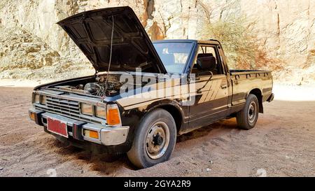 Ägypten, Sharm El Sheikh - 7. Juni 2019: Ein alter schwarzer Pickup-Truck in der Wüste mit offener Motorhaube. Stockfoto