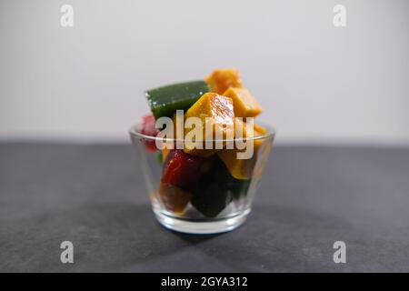 Glas mit farbenfroher mexikanischer Fruchtpaste auf schwarzer Oberfläche Stockfoto