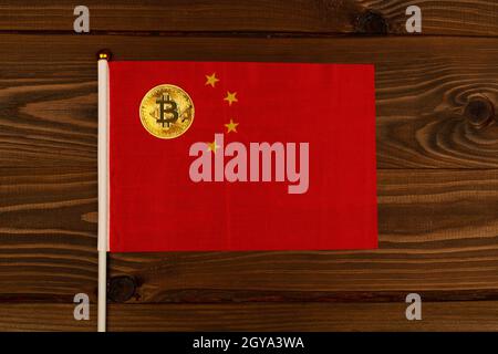 Goldbitcoin Kryptowährung Münze auf Flagge von China auf hölzernen braunen Hintergrund. Das Konzept des Hauptlandes für legale Kryptowährungs-Bergbaufarmen Stockfoto