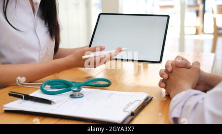 Arzt, der ein Tablet-PC verwendet, diskutierte etwas mit dem Patienten. Stockfoto
