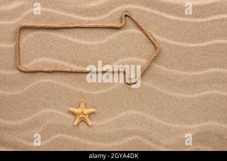 Zeiger aus Seil und Muschel auf dem Sand, mit Platz für Ihren Text Stockfoto