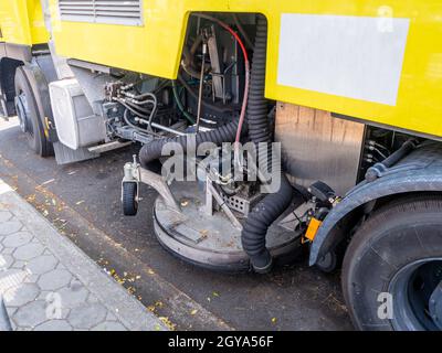 Ein Auto für die Reinigung von Straßen mit runden Bürsten auf einer Stadtstraße. Stockfoto