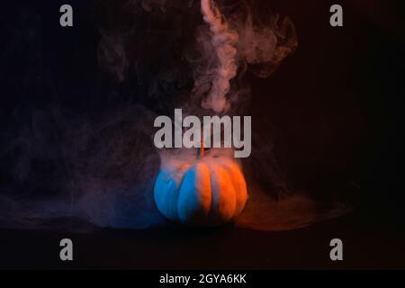 Halloween Kürbis mit Rauch und Neonlicht auf schwarzem Hintergrund. Minimalkonzept. Stockfoto