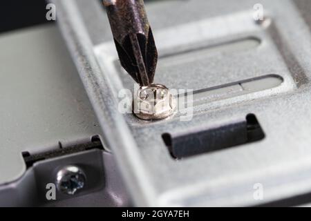Schraubendreher, mit dem eine Schraube eines pcs auf der Festplattenseite gelöst wird Stockfoto