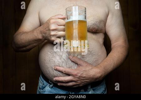 Ein Mann mit einem großen Bauch und einem Becher Bier in der Hand Stockfoto