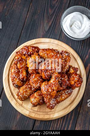 Knusprig orange glasierte Hähnchenflügel mit blauer Käsesauce auf dem Holzbrett Stockfoto