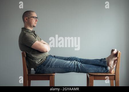 Der Mann, der auf den Stühlen saß und auf das Fenster schaute. Stockfoto