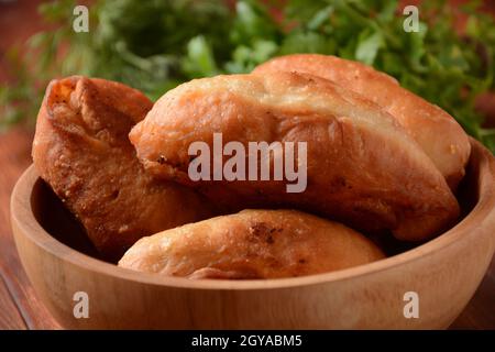 Russische Patties (Pasties, heiße Kuchen, Pirozhki, Pies) auf Holzschrank . Traditionelle hausgemachte gebratene Kuchen mit Kartoffeln Stockfoto