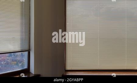 Jalousien sind am Fenster befestigt, um im Innenbereich vor Hitze und Sonnenlicht zu schützen. Rollläden im Haus fangen Sonnenlicht ein Stockfoto