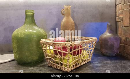 Große Glasvasen, ein Korb mit Äpfeln und Tellern im Inneren einer modernen Küche. Die Kombination von Holz und Beton im Design. Moderner Stall Stockfoto