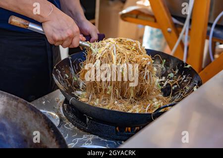 Herstellung von asiatischen Nudeln im Wok im Freien auf offene Küche odprta kuhna Gastronomie-Veranstaltung . Stockfoto