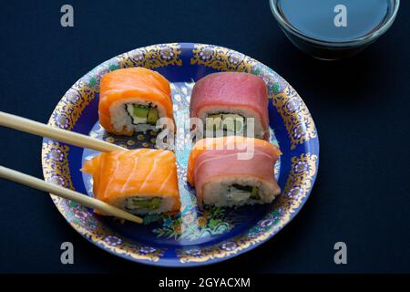 Kalifornische Sushi-Rollen mit Avocado, Gurke und Käse, eingewickelt in Lachs und Thunfisch Stockfoto