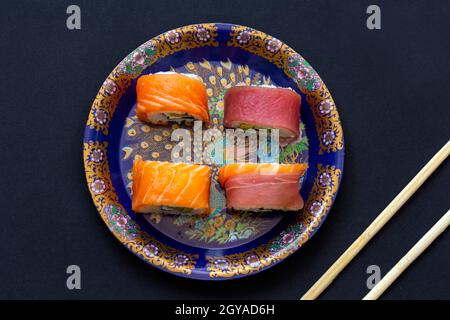 Kalifornische Sushi-Rollen mit Avocado, Gurke und Käse, eingewickelt in Lachs und Thunfisch Stockfoto