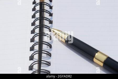 Extreme Nahaufnahme eines Stiftes, der über einem offenen Spiralnotizbuch oder einem persönlichen Organizer platziert wird. Blick auf den hohen Engel. Business Education-Hintergrund. Stockfoto