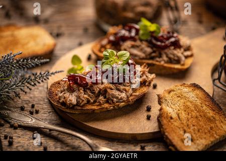 Köstliche gezogene Ente mit karamellisiertem Zwiebelchutney auf rustikalem Holzhintergrund Stockfoto