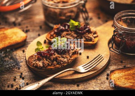 Belegte Entenbrötchen mit karamellisierten Zwiebeln, serviert auf knusprigem Brot Stockfoto