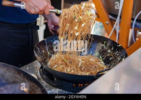 Herstellung von asiatischen Nudeln im Wok im Freien auf offene Küche odprta kuhna Gastronomie-Veranstaltung . Stockfoto