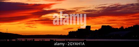 Orangefarbener und roter Sonnenaufgang über einem Hafen Stockfoto