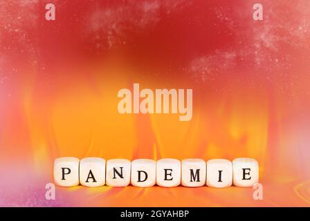 Das deutsche Wort für Pandemie in Holzwürfeln, rotem und orangenem Flammenhintergrund Stockfoto