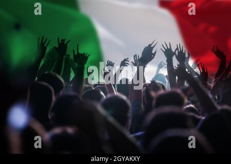 Fußballfans, die Italien unterstützen - Publikum feiert im Stadion mit erhobenen Händen gegen die italienische Flagge Stockfoto