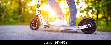 Frau Reiten auf Roller im Park im Sommer. Städtischer Ökotransport Stockfoto
