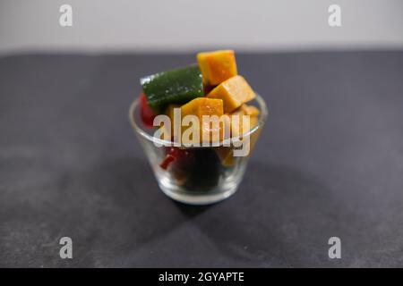 Glas mit farbenfroher mexikanischer Fruchtpaste auf schwarzer Oberfläche Stockfoto