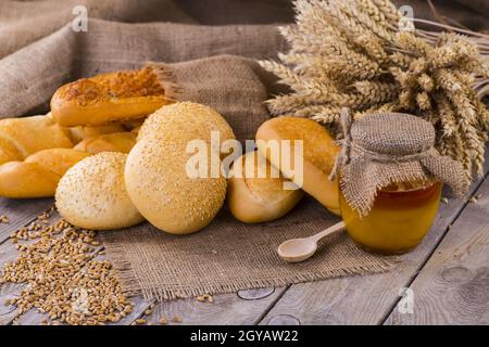 Honig in einem Glas, Scheibe Brot, Weizen und Milch auf einem alten Vintage-Holztisch von oben. Frühstück im ländlichen oder rustikalen Stil. Hintergrund la Stockfoto