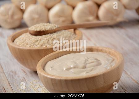 Tahini und Sesam in Holzschüsseln auf Holztisch. Stockfoto