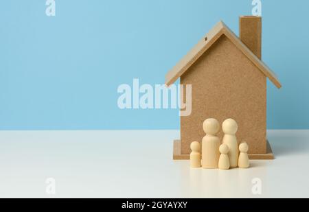 Hölzerne Familienfiguren, Modellhaus. Immobilienkauf, Mietkonzept. Umzug in neue Wohnungen, Platz kopieren Stockfoto