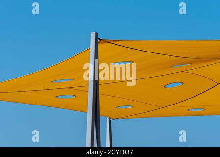 Stoffe, um die Sonne zu bedecken und Schatten zu bilden, mit dreieckigen Formen. Gestreckter Sonnenschutz aus Stoff Stockfoto