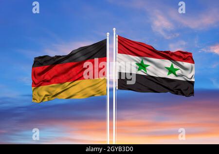 Deutschland und Syrien zwei Flaggen auf Fahnenmasten und blau bewölkt Himmel Stockfoto