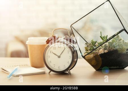 Klassischer Vintage-Wecker und Kaffeetasse auf Holzhintergrund Stockfoto