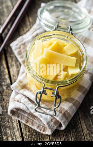 In Scheiben geschnittene Bambusdosensprossen im Glas auf einem Holztisch. Stockfoto