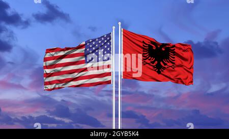 Albanien und United Flaggenstaaten winken im Wind gegen Weiße bewölkt blauer Himmel zusammen. Diplomatie Konzept, internationale Beziehungen. Stockfoto