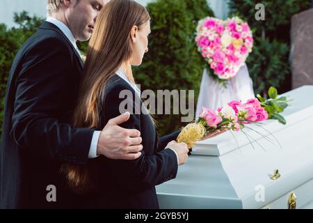 Trauer um Mann und Frau auf der Trauerfeier am Sarg oder Sarg mit rosa rose Stockfoto