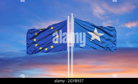 Europäische Union und Somalia zwei Flaggen auf Fahnenmasten und blau wolkiger Himmel Stockfoto