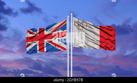 Die britische und die maltesische Flagge winken im Wind gegen den weißen, wolkigen blauen Himmel. Diplomatie Konzept, internationale Beziehungen Stockfoto