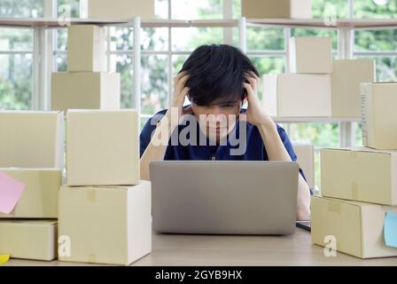 Der traurige Unternehmer hält seinen Tempel mit beiden Händen und sitzt im Büro. Das Konzept von Arbeitslosen, Traurigkeit, Depressionen und menschlichen Problemen. Stockfoto