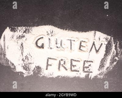 Glutenfrei in Mehl auf einem dunklen Stein Küchentisch geschrieben, gesundes Lebensmittelkonzept Stockfoto