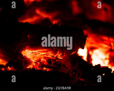 Rote Hitze von Holzkohle brennendem Holz im Dunkeln. Feuer. Hintergrundbild. Platz für Text. Stockfoto