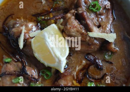 Nahaufnahme des traditionellen pakistanischen Haleem-Gerichts mit Salat und Zitronensaft. Stockfoto