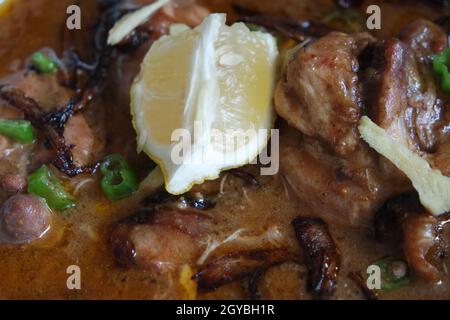 Nahaufnahme des traditionellen pakistanischen Haleem-Gerichts mit Salat und Zitronensaft. Stockfoto