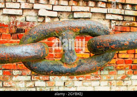 Glieder einer eisernen Kette auf einem Backstein Wand Hintergrund. Hintergrundbild. Abstraktes Foto. Für Text platzieren. Poster. Broschüre. Magazindeckel. Für Text platzieren. Stockfoto