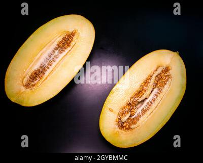 Gelbe Melone mit einem Messer auf schwarzem Hintergrund geschnitten. Food-Foto. Melonenkultur. Landwirtschaft. Ort für Ihren Text. Schwarzer Hintergrund. Hintergrundbild. Stockfoto