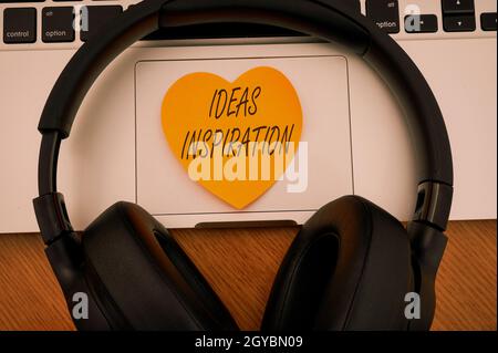 Handschrift Zeichen Ideen Inspiration, Geschäftskonzept Gefühl der Begeisterung, die Sie von jemandem oder etwas Blank Notepad Laptop mit Stift und Headph Stockfoto