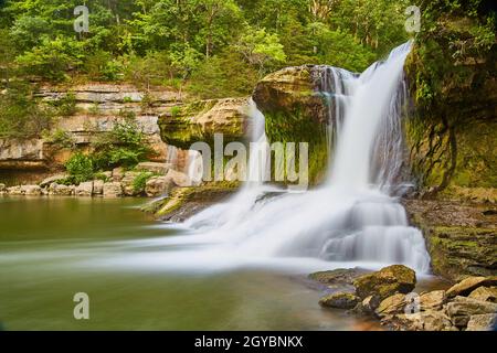 Falls in a jungle type setting with moss on rocks and deep green forest Stockfoto